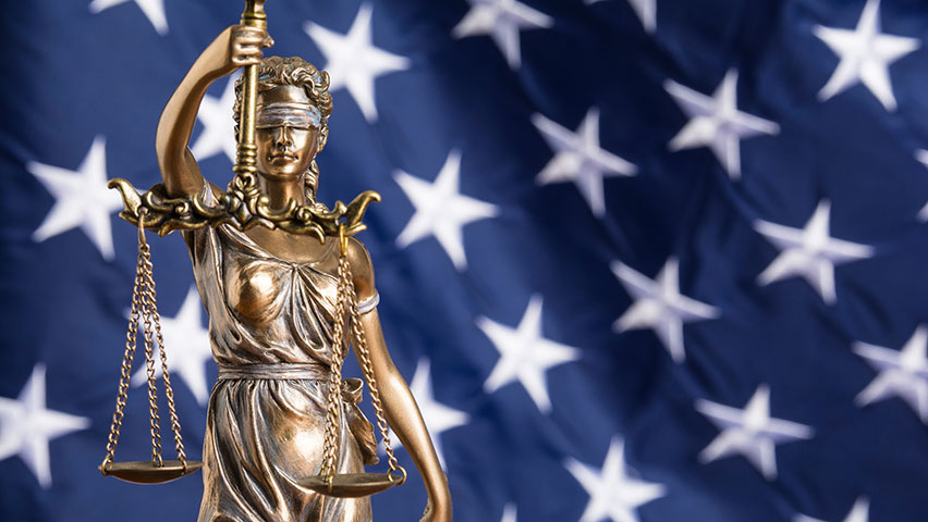 blindfolded goddess of justice against the flag of the United States of America