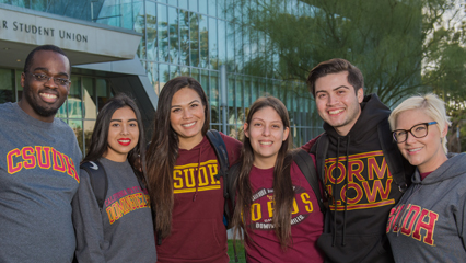Five CSUDH smiling students in front of Loker Student Union