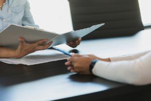 two workers review a case file folder and working online