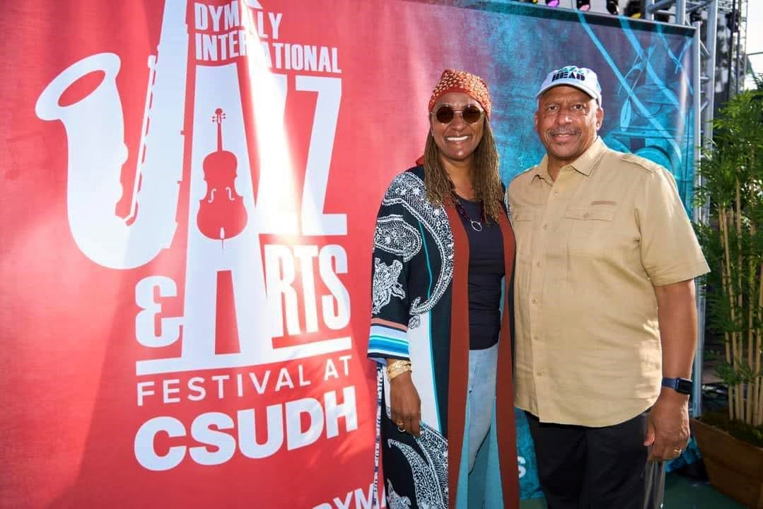 Two attendees taking a photo in front of a Jazz Festival Banner