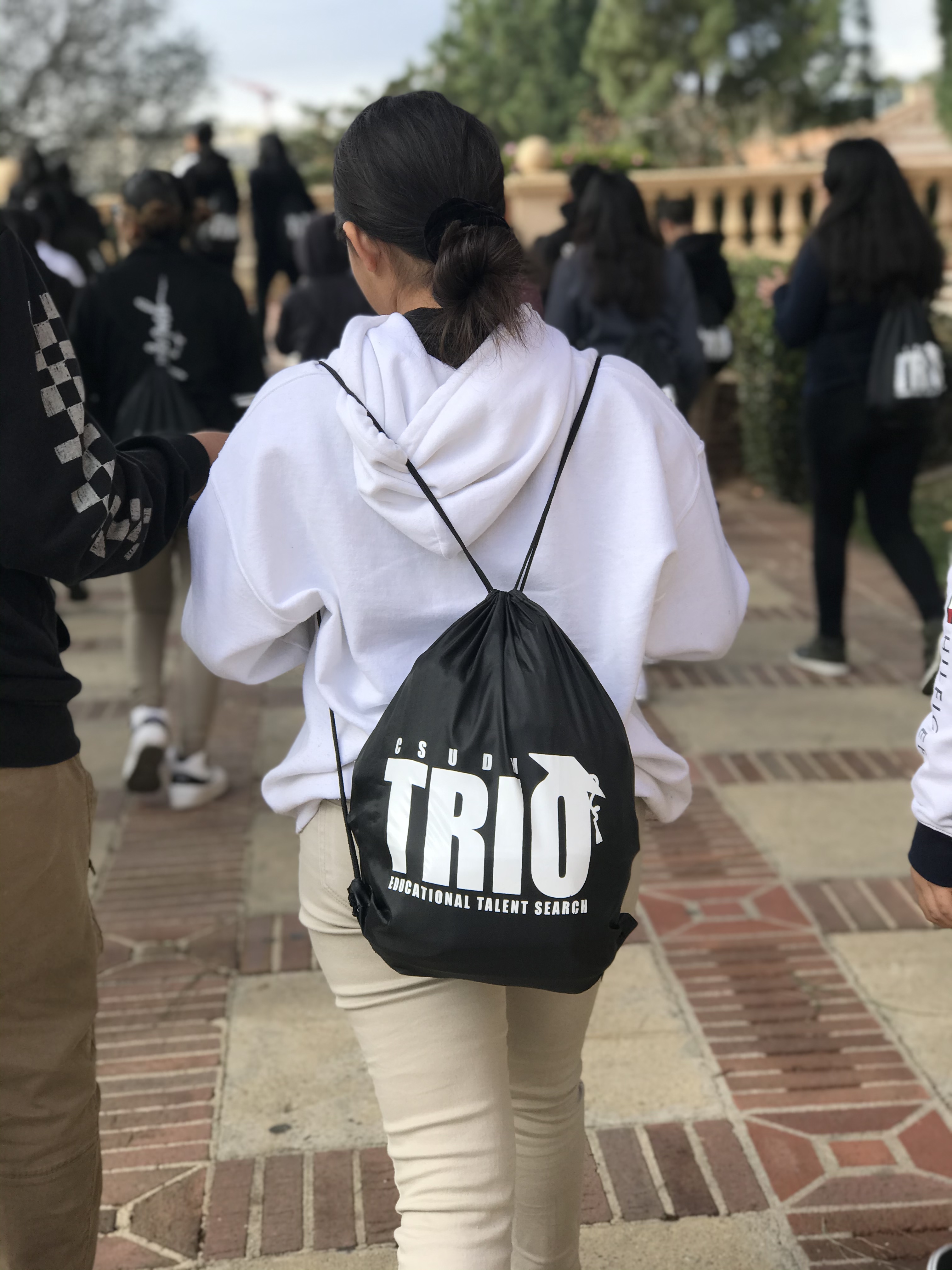 CSUDH-ETS Student Participant wearing an ETS string bag, as they walk on a path at a university.
