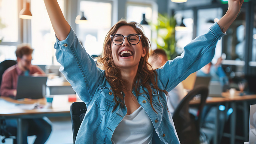 Young woman very happy with arms stretched above sitting in office
