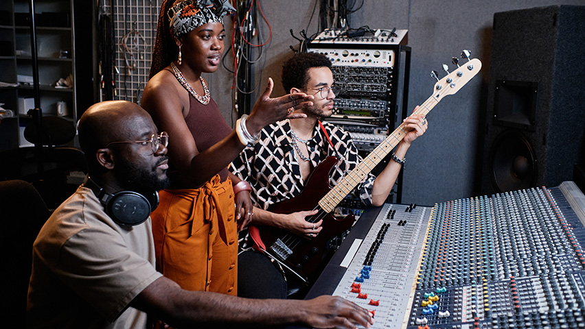 Male Music producer, female singer and male guitarist in recording studio
