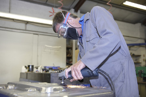 Man in work coveralls working with metal machinery